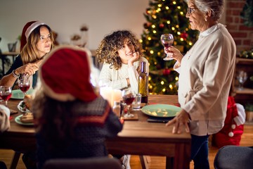 Beautiful group of women smiling happy and confident. On of them holding cup of wine speaking speech celebrating christmas at home