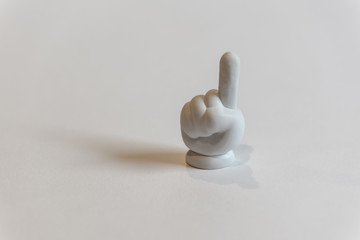 Small white toy hand with index finger pointing up in the 