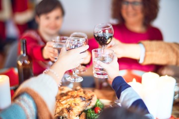 Beautiful family smiling happy and confident. Eating roasted turkey toasting with cup of wine celebrating christmas at home