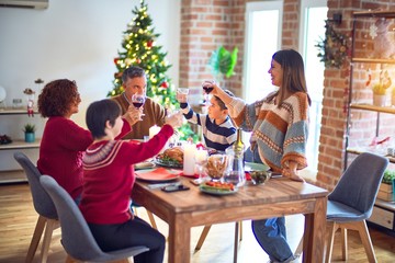 Beautiful family smiling happy and confident. One of them standing holding cup of wine speaking speech celebrating christmas at home