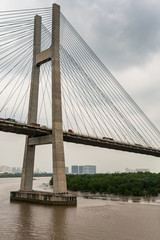 Ho Chi Minh City, Vietnam - March 12, 2019: Long Tau and song Sai Gon rivers meeting point. Closeup of  H-shaped pylon of Phu My suspension bridge under gray cloudscape. 