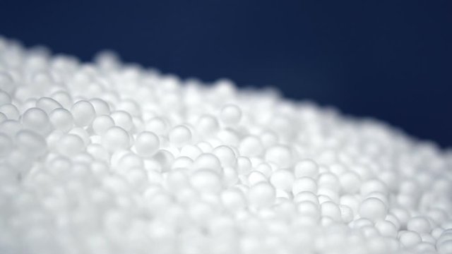 White round polystyrene packaging material drop from injection machine in slow motion, modern foam bead ball decoration cause global warming from chemical waste
