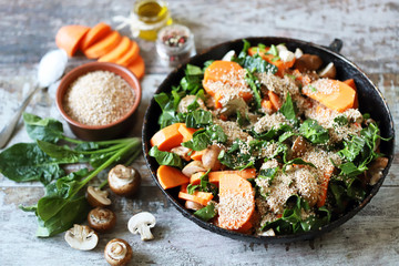 Cooking vegan wheat porridge with vegetables and mushrooms. Vegan dish before cooking. Carrots, wheat groats, champignons, spinach, spices.