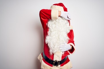 Middle age handsome man wearing Santa costume standing over isolated white background covering eyes with arm smiling cheerful and funny. Blind concept.
