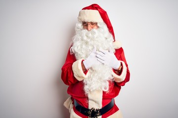 Middle age handsome man wearing Santa costume standing over isolated white background smiling with hands on chest with closed eyes and grateful gesture on face. Health concept.