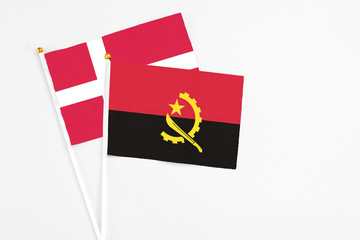 Angola and Denmark stick flags on white background. High quality fabric, miniature national flag. Peaceful global concept.White floor for copy space.