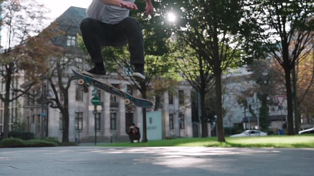 skateboarder doing flip trick in super slow motion at downtown city reflecting sun