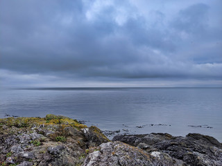 Rocky coastal shoreline of Friday Harbor in San Juan Island, WA, on an overcast day