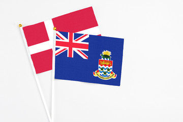 Fototapeta premium Cayman Islands and Denmark stick flags on white background. High quality fabric, miniature national flag. Peaceful global concept.White floor for copy space.