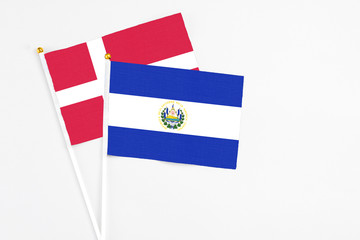 El Salvador and Denmark stick flags on white background. High quality fabric, miniature national flag. Peaceful global concept.White floor for copy space.