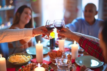 Beautiful family smiling happy and confident. Eating roasted turkey and toasting with cup of wine celebrating Thanksgiving Day at home