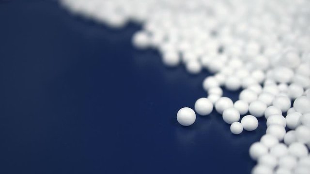 White round polystyrene packaging material drop from injection machine in slow motion, modern foam bead ball decoration cause global warming from chemical waste