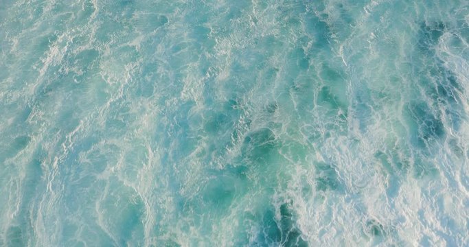 Aerial top down view flying over a breaking wave with ocean white water in motion and foam textures, ocean texture background