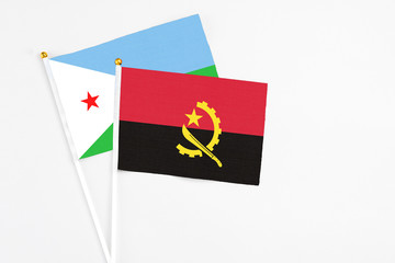 Angola and Djibouti stick flags on white background. High quality fabric, miniature national flag. Peaceful global concept.White floor for copy space.