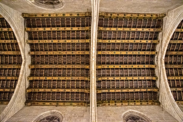 Looking up at a wood rafter ceiling with stone arches from a cathedral in Barcelona, Spain