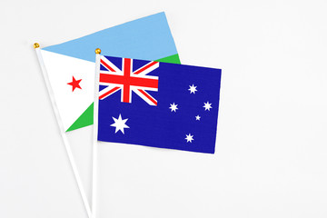 Fototapeta premium Australia and Djibouti stick flags on white background. High quality fabric, miniature national flag. Peaceful global concept.White floor for copy space.