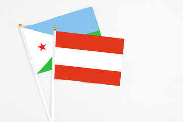 Austria and Djibouti stick flags on white background. High quality fabric, miniature national flag. Peaceful global concept.White floor for copy space.