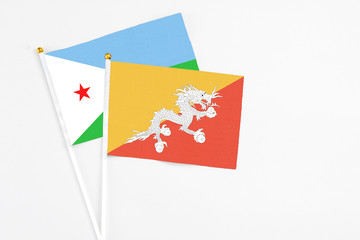 Bhutan and Djibouti stick flags on white background. High quality fabric, miniature national flag. Peaceful global concept.White floor for copy space.