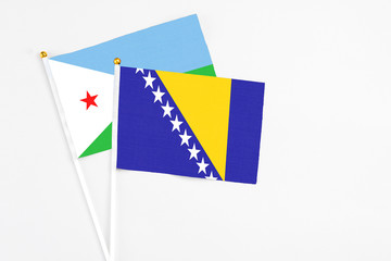 Bosnia Herzegovina and Djibouti stick flags on white background. High quality fabric, miniature national flag. Peaceful global concept.White floor for copy space.
