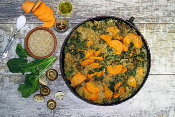 Vegan wheat porridge with vegetables and mushrooms. Vegan dish before cooking. Carrots, wheat groats, champignons, spinach, spices.