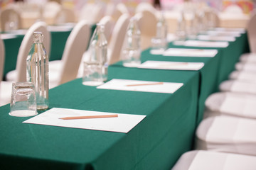 Selective focus of Paper, pencil, water bottle, glass  on the table in the seminar room background