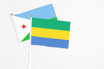 Gabon and Djibouti stick flags on white background. High quality fabric, miniature national flag. Peaceful global concept.White floor for copy space.
