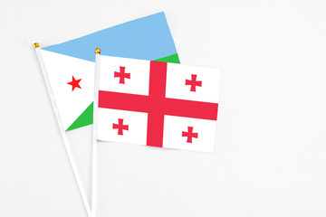 Georgia and Djibouti stick flags on white background. High quality fabric, miniature national flag. Peaceful global concept.White floor for copy space.