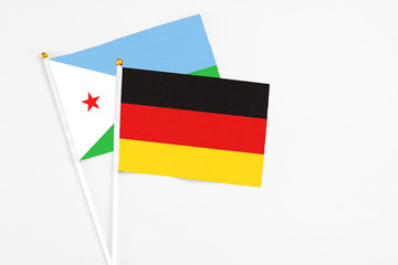 Germany and Djibouti stick flags on white background. High quality fabric, miniature national flag. Peaceful global concept.White floor for copy space.