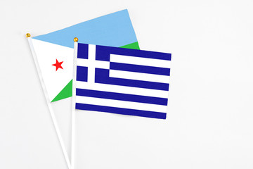 Greece and Djibouti stick flags on white background. High quality fabric, miniature national flag. Peaceful global concept.White floor for copy space.