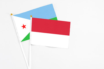 Indonesia and Djibouti stick flags on white background. High quality fabric, miniature national flag. Peaceful global concept.White floor for copy space.