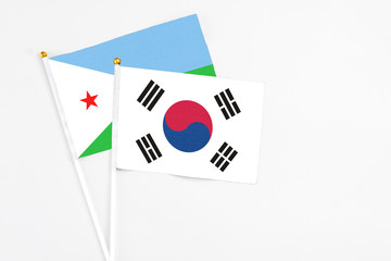 South Korea and Djibouti stick flags on white background. High quality fabric, miniature national flag. Peaceful global concept.White floor for copy space.