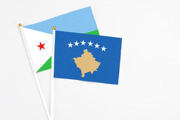 Kosovo and Djibouti stick flags on white background. High quality fabric, miniature national flag. Peaceful global concept.White floor for copy space.