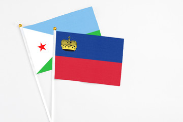 Liechtenstein and Djibouti stick flags on white background. High quality fabric, miniature national flag. Peaceful global concept.White floor for copy space.