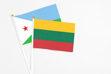 Lithuania and Djibouti stick flags on white background. High quality fabric, miniature national flag. Peaceful global concept.White floor for copy space.