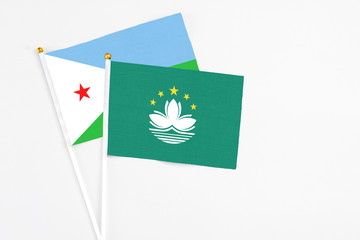 Macao and Djibouti stick flags on white background. High quality fabric, miniature national flag. Peaceful global concept.White floor for copy space.