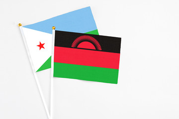 Malawi and Djibouti stick flags on white background. High quality fabric, miniature national flag. Peaceful global concept.White floor for copy space.