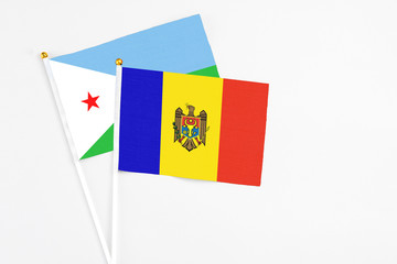 Moldova and Djibouti stick flags on white background. High quality fabric, miniature national flag. Peaceful global concept.White floor for copy space.