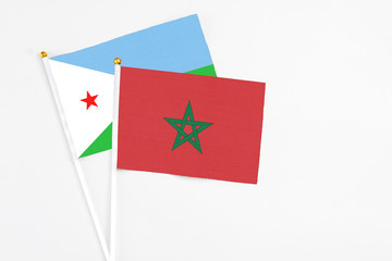 Morocco and Djibouti stick flags on white background. High quality fabric, miniature national flag. Peaceful global concept.White floor for copy space.