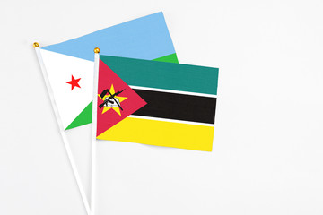 Mozambique and Djibouti stick flags on white background. High quality fabric, miniature national flag. Peaceful global concept.White floor for copy space.