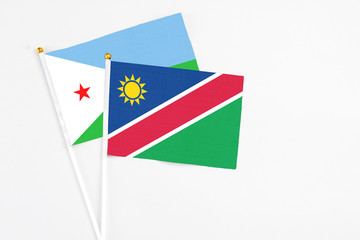 Namibia and Djibouti stick flags on white background. High quality fabric, miniature national flag. Peaceful global concept.White floor for copy space.