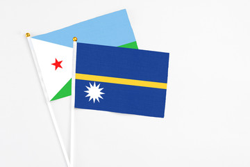 Nauru and Djibouti stick flags on white background. High quality fabric, miniature national flag. Peaceful global concept.White floor for copy space.