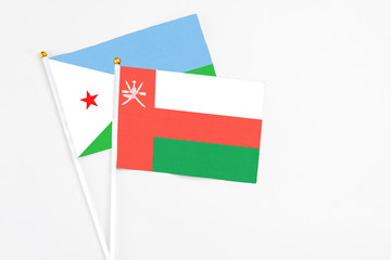 Oman and Djibouti stick flags on white background. High quality fabric, miniature national flag. Peaceful global concept.White floor for copy space.