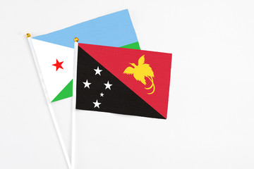Papua New Guinea and Djibouti stick flags on white background. High quality fabric, miniature national flag. Peaceful global concept.White floor for copy space.