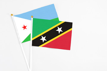 Saint Kitts And Nevis and Djibouti stick flags on white background. High quality fabric, miniature national flag. Peaceful global concept.White floor for copy space.