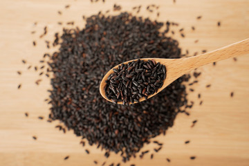 black rice pile and wooden spoon on wooden table