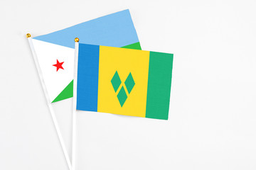 Saint Vincent And The Grenadines and Djibouti stick flags on white background. High quality fabric, miniature national flag. Peaceful global concept.White floor for copy space.