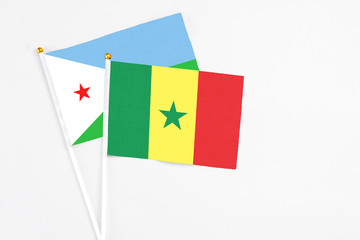 Senegal and Djibouti stick flags on white background. High quality fabric, miniature national flag. Peaceful global concept.White floor for copy space.