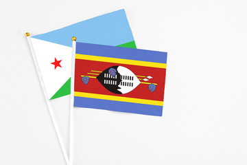 Fototapeta premium Swaziland and Djibouti stick flags on white background. High quality fabric, miniature national flag. Peaceful global concept.White floor for copy space.