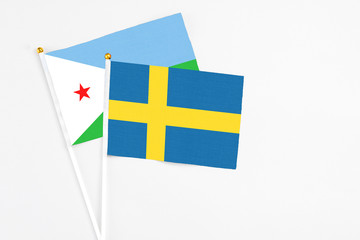 Sweden and Djibouti stick flags on white background. High quality fabric, miniature national flag. Peaceful global concept.White floor for copy space.