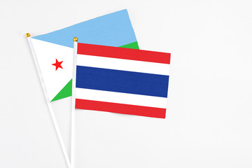 Thailand and Djibouti stick flags on white background. High quality fabric, miniature national flag. Peaceful global concept.White floor for copy space.